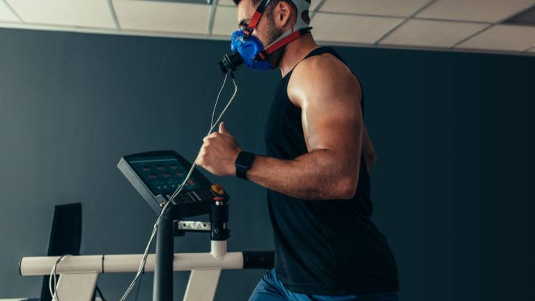 A man running on a treadmill wearing a VO2 max testing mask, measuring his oxygen consumption and fitness level in a gym setting.