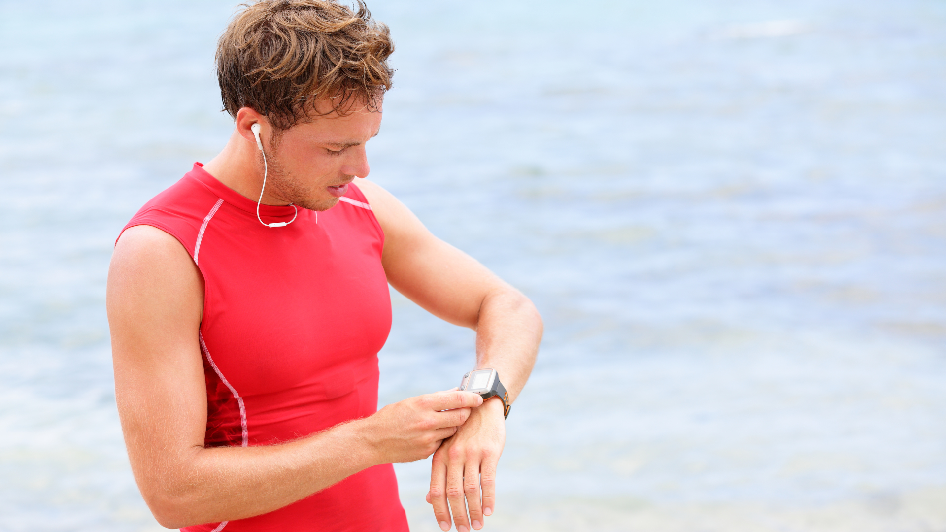 A man taking his pulse while exercising on the beach.